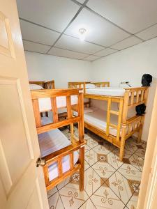 Hostal Villa Marta في سانتا آنا: غرفة بها ثلاثة أسرة بطابقين وباب