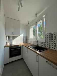 a kitchen with white cabinets and a sink and a window at Apartament wakacyjny Brzeźno in Gdańsk