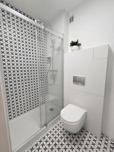 a white bathroom with a shower and a toilet at Apartament wakacyjny Brzeźno in Gdańsk