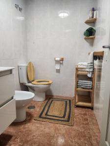 a bathroom with a white toilet and a rug at Diamante de la Bahia in Caleta De Fuste