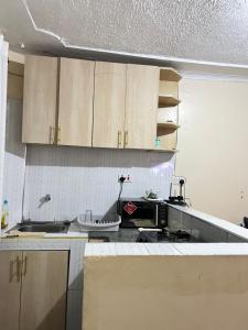 uma cozinha com armários de madeira e um balcão preto em The comfort place Eldy em Eldoret