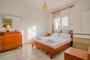 a bedroom with a bed with a dresser and a window at Panos house in Hanioti