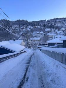a snow covered road in a town with houses at Stort, koselig hus i naturområde in Bergen