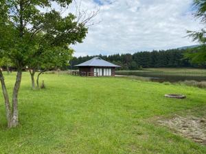 a building in the middle of a field with a tree at eKuthuleni - Wooden Cabin over the dam in Howick