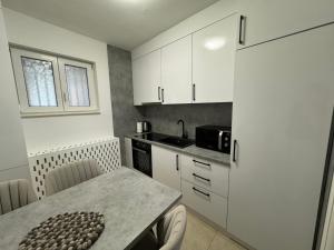 una pequeña cocina con armarios blancos y una mesa en Estrada Apartment, en Sarajevo