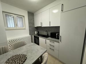 a small kitchen with white cabinets and a table at Estrada Apartment in Sarajevo +7 photos