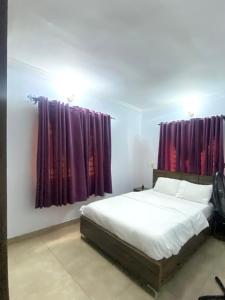 1 Schlafzimmer mit einem weißen Bett und lila Vorhängen in der Unterkunft Amazing Grace Apartment in Ikeja