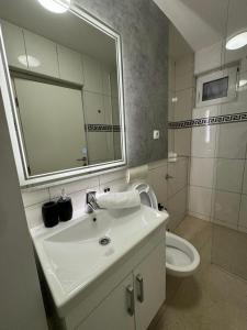 y baño con lavabo, aseo y espejo. en Estrada Apartment, en Sarajevo