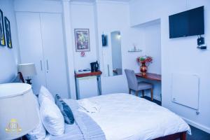 a hotel room with a bed and a table and a desk at Royal Highness Lux Guesthouse in Carletonville