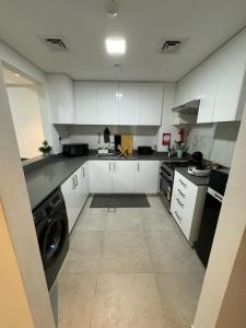 a large kitchen with white cabinets and a washer at Al jada apartment Sharjah in Sharjah