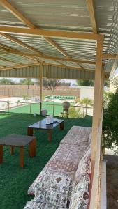 a covered patio with a table and a bench at مزرعه فلج المعلا in Falaj al Mu‘allá