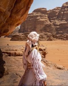 a woman is standing in the desert at WADi RUM MAGIC CAMP in Wadi Rum