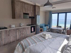 a bedroom with a bed and a kitchen with a view at WavesEnd Wilderness Self-catering Units in Wilderness