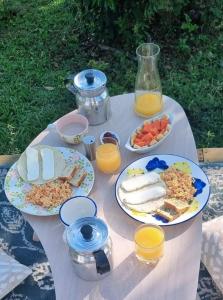 a table with plates of food and glasses of orange juice at Rainbow Glamping in Abejorral