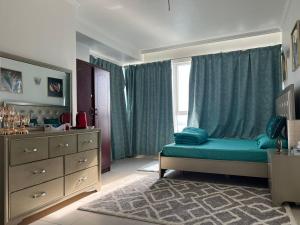 a bedroom with a bed and a dresser and a window at Burj Al saadah Al mamzar sharjah in Sharjah