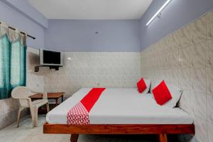 a bedroom with a bed with red pillows and a tv at OYO Flagship Sai Ganesh Deluxe Lodge in Tirupati