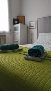 a bed with two green blankets on top of it at Casa Alderotti in Bologna