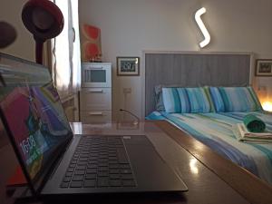 um computador portátil sentado numa secretária ao lado de uma cama em Casa Alderotti em Bolonha