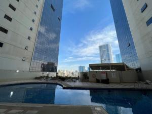 une piscine au milieu de deux grands bâtiments dans l'établissement Burj Al saadah Al mamzar sharjah, à Charjah