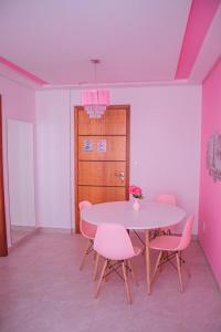 een eetkamer met een tafel en roze stoelen bij Apartamento rosa in Guarapari