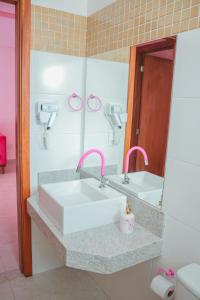 een badkamer met een witte wastafel en een spiegel bij Apartamento rosa in Guarapari