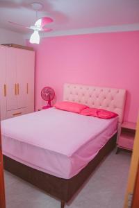 een roze slaapkamer met een groot bed en een roze muur bij Apartamento rosa in Guarapari