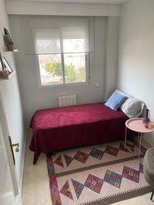 1 dormitorio con cama roja y ventana en Apartamentos Oasis, en Albir