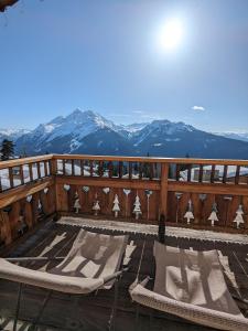 a deck with chairs and mountains in the background at Chalet Lè Lodzé - Pieds des pistes in La Rosière