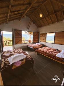 um quarto com duas camas e janelas em Hotel Rancho Maju em San Agustín
