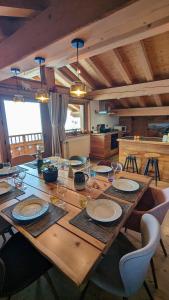 a wooden table with plates and wine glasses on it at Chalet Lè Lodzé - Pieds des pistes in La Rosière