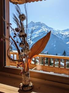 a vase with flowers in a window with a mountain at Chalet Lè Lodzé - Pieds des pistes in La Rosière
