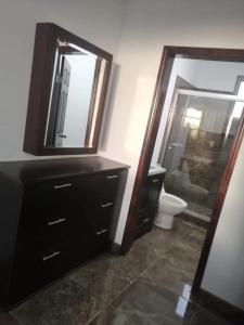 een badkamer met een wastafel, een toilet en een spiegel bij Paloma in Ensenada