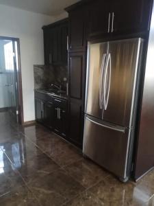 uma cozinha com um frigorífico de aço inoxidável e armários pretos em Paloma em Ensenada