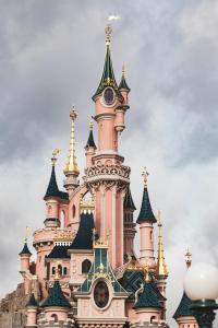 Un castillo rosa con una torre de reloj encima. en Appartement proche Disneyland, en Bailly-Romainvilliers