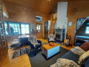 a living room with a couch and chairs and a fireplace at Villa kitkanhelmi in Kuusamo