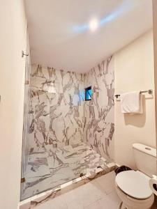 La salle de bains est pourvue d'une douche et d'un mur en marbre. dans l'établissement Hotel Casa 20, à León