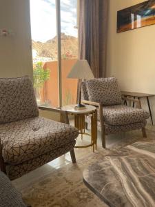 a living room with two chairs and a table and a window at فيلا بمزرعة in AlUla