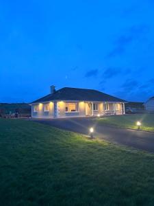 uma casa com luzes no relvado à noite em Valley view em Gort