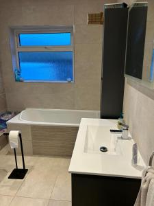 uma casa de banho com um lavatório, uma banheira e uma janela. em Valley view em Gort
