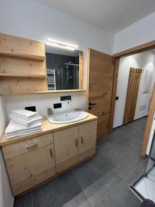 W łazience znajduje się umywalka i lustro. w obiekcie Dolomia Apartments & Spa w mieście Dimaro