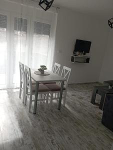 einen Esstisch mit weißen Stühlen und einen TV in der Unterkunft Vila Leona D-1 in Divčibare