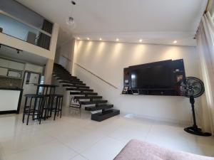a living room with a flat screen tv and stairs at Casa da lagoa in Porto Seguro