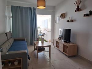 ein Wohnzimmer mit einem Sofa, einem TV und einem Tisch in der Unterkunft Luxury Sea View Senator Lanzarote in Costa Teguise