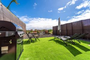 a backyard with a grill and chairs and a table and umbrella at SUNSHINE VILLA in Lajares