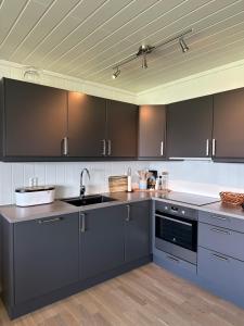 a kitchen with gray cabinets and a sink at Apartment with beautiful panoramic view in Skulestadmo