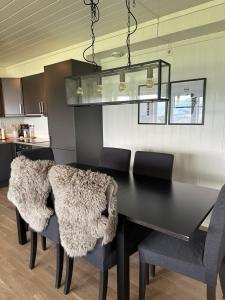a black dining room table with chairs and a chandelier at Apartment with beautiful panoramic view in Skulestadmo