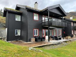 una casa negra con una terraza con sillas. en Apartment with beautiful panoramic view, en Skulestadmo