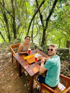 a man and woman sitting at a wooden table at Rock n Fall Nature Resort in Ella