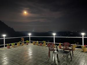 a table and chairs on a balcony at night at EcoEscape Mukteshwar in Mukteshwar