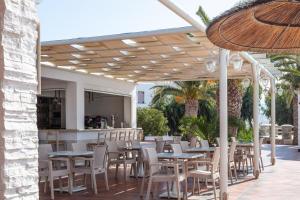 a restaurant with tables and chairs under a pavilion at Kavuras Village in Agios Prokopios